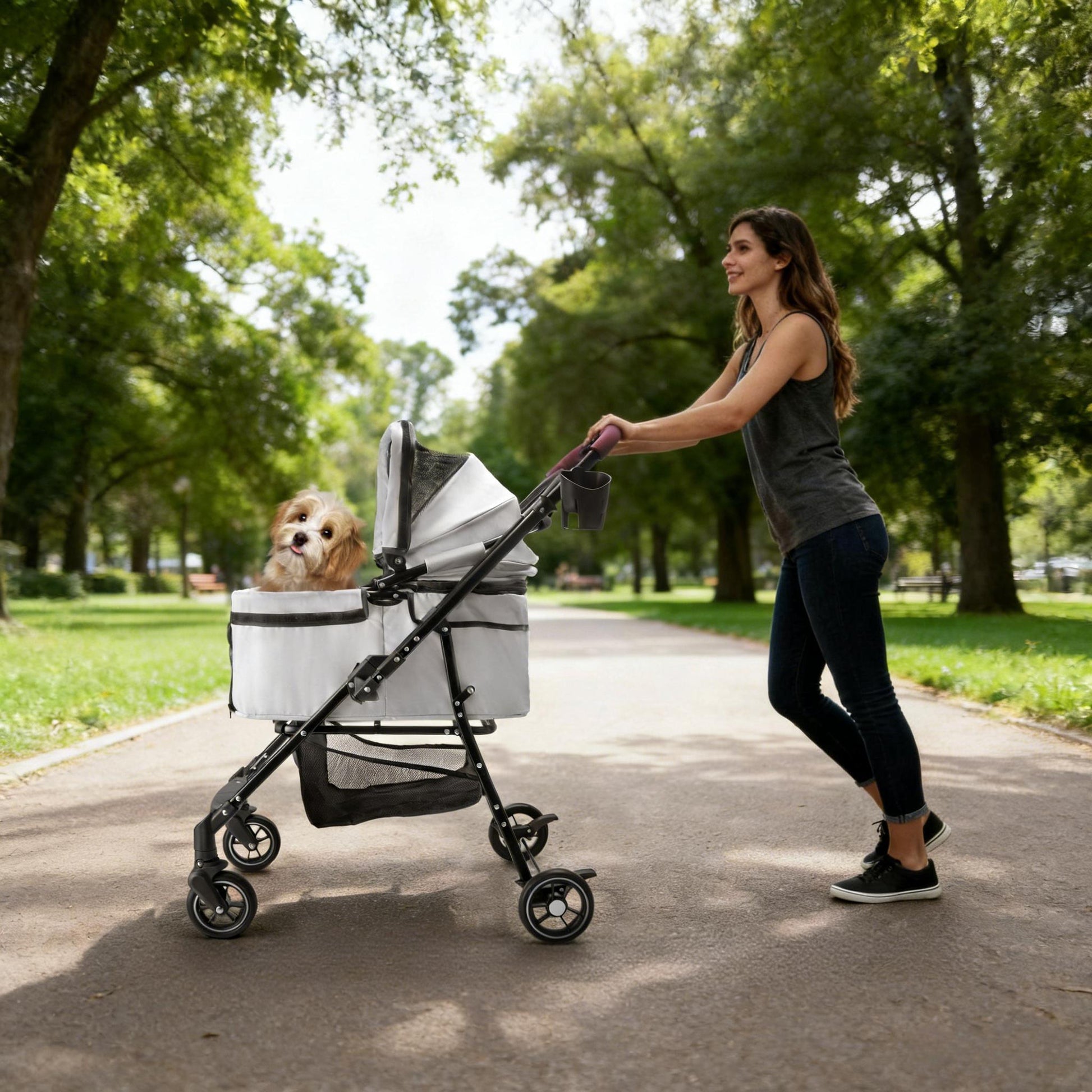 Woman pushing a pet stroller with a dog in it through a park.